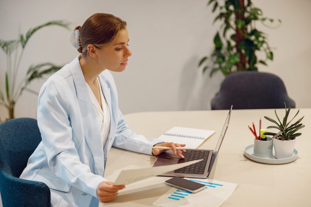 A Professional Woman Engaged in Work with Her Laptop Within a Modern Office Setting
